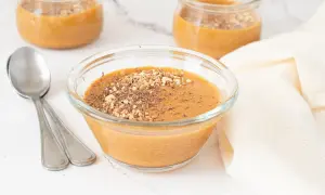 Delicioso postre cremoso, como baba de camelo, servido en un cuenco de cristal con nueces picadas y virutas de chocolate.
