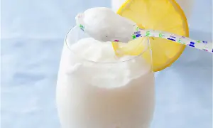 Refrescante sorbete de limón al cava, servido en copa con rodaja de limón y cuchara decorada.