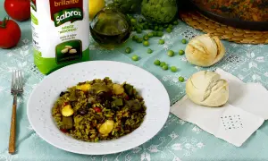 Un plato de paella de verduras, con arroz Sabroz, tomates, alcachofas, guisantes y panecillos.