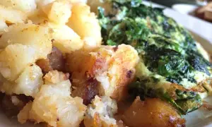 Patatas doradas y crujientes junto a unas espinacas con patatas, un plato casero y reconfortante.