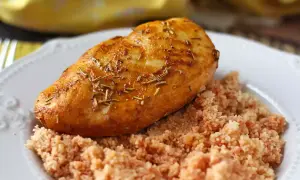 Pechuga de pollo dorada y jugosa, cocinada en freidora de aire, servida sobre una cama de cuscús.