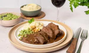 Carrilleras de ternera en salsa, un plato reconfortante que evoca la auténtica receta de la abuela, acompañado de puré de patatas y guisantes.