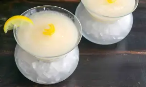 Dos copas de sorbete de limón, una con rodaja y otra con espiral de limón, servidas sobre hielo picado.