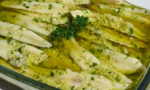 Boquerones en vinagre, frescos y listos para disfrutar, con ajo picado y perejil en aceite de oliva.