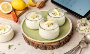 Delicioso mousse de limón Thermomix en vasitos, decorado con limón y tomillo. ¡Perfecto para un postre refrescante!