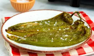 Pimientos verdes asados en freidora de aire, servidos en plato blanco con sal gruesa.