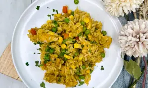 Arroz con pollo de la abuela, un plato casero con pollo tierno, guisantes, maíz y zanahoria, espolvoreado con perejil fresco.