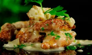 Deliciosas albóndigas de rape doradas, cubiertas con una cremosa salsa y perejil fresco.