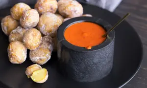 Papas arrugadas cubiertas de sal marina, listas para ser sumergidas en una salsa roja picante.