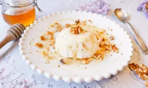 Delicioso postre de mel i mató con nueces y miel, servido en un plato blanco con borde festoneado.