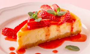 Deliciosa tarta de fresas con nata y queso Philadelphia, cubierta con salsa de fresa y hojas de menta.