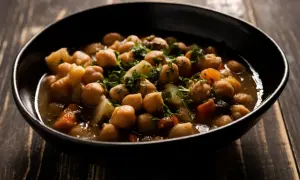 Un tazón de garbanzos con patatas y zanahoria, adornado con perejil fresco. Una deliciosa receta de garbanzos tradicional.