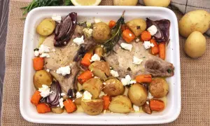Chuletas de cerdo al horno con patatas, zanahorias, cebolla morada y queso feta. Un plato sabroso y completo.