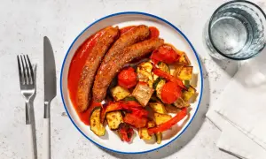 Salchichas con tomate y verduras asadas, un plato sabroso y saludable.