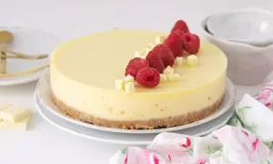 Tarta de chocolate blanco decorada con frambuesas frescas y trocitos de chocolate.