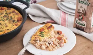 Un delicioso arroz con costra recién hecho, con trozos de salchicha y garbanzos, servido en un plato blanco.