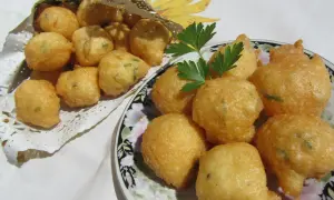 Buñuelos de bacalao hechos en Thermomix, dorados y crujientes, servidos en un plato y en un cono dorado.