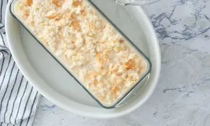 Preparando una deliciosa receta de pudin casero en un molde de vidrio, con trozos de galleta integrados.