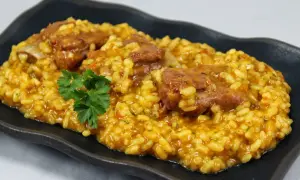 Arroz con costillas jugosas, preparado en Thermomix, servido en plato negro con perejil fresco.