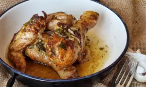 Sabroso pollo al ajillo dorado y jugoso, bañado en su propio jugo con ajo y hierbas, servido en una cazuela.