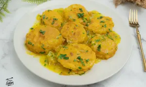 Patatas a la importancia, doradas y tiernas, bañadas en una salsa amarilla con perejil picado. Un plato que demuestra la importancia de las patatas en la cocina.
