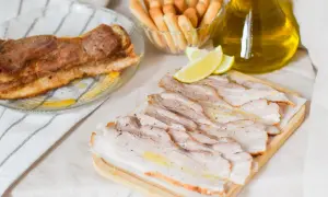 Chicharrón de Cádiz, lonchas de panceta asada, palitos de pan y limón, todo listo para disfrutar.