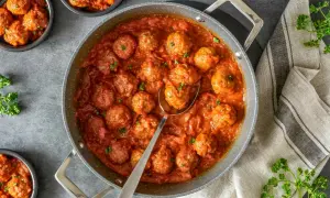 Sabrosas almondigas en salsa roja, recién servidas en una sartén, con perejil fresco espolvoreado. ¡Un plato casero irresistible!