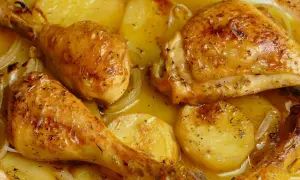Pollo al horno con patatas, dorado y jugoso, con hierbas aromáticas y cebolla. Un plato casero irresistible.