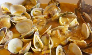 Un plato humeante de almejas a la marinera, con su salsa dorada y trozos de ajo. ¡Un manjar!