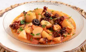 Un delicioso pulpo a la mugardesa, con patatas tiernas y un sofrito sabroso, adornado con perejil fresco.