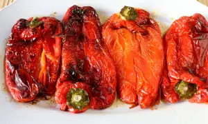 Pimientos rojos asados en freidora de aire, con piel arrugada y un brillo apetitoso.