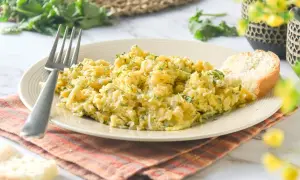 Un plato de revuelto de bacalao con perejil picado, acompañado de una rebanada de pan y un tenedor.