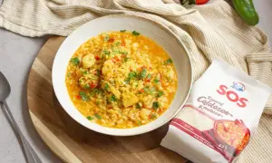 Un plato de arroz con bacalao, pimientos y perejil, acompañado de un paquete de arroz SOS especial caldosos.
