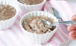Delicioso arroz con leche de soja en cuencos blancos, con una cuchara lista para probar.