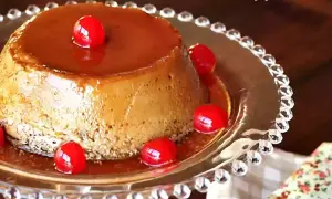 Delicioso flan de café con caramelo líquido y cerezas rojas, servido en un plato de cristal decorado.