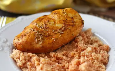 Pechuga de pollo dorada y jugosa, cocinada en freidora de aire, servida sobre una cama de cuscús.