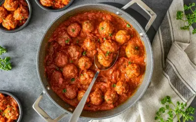 Sabrosas almondigas en salsa roja, recién servidas en una sartén, con perejil fresco espolvoreado. ¡Un plato casero irresistible!