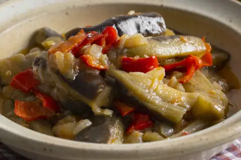 Berenjenas en escabeche, un plato casero con trozos de berenjena, pimientos rojos y cebolla en una salsa sabrosa.