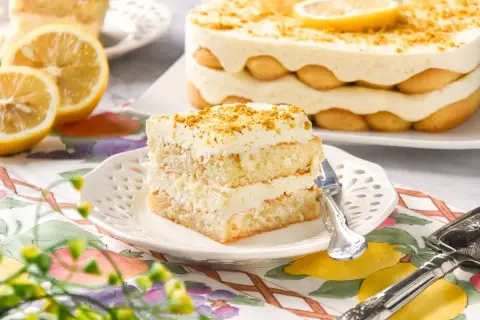 Delicioso tiramisú de limón, con capas de bizcocho, crema y soletillas, decorado con ralladura y rodajas de limón.