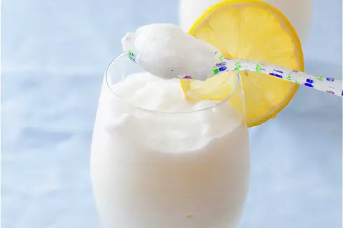 Refrescante sorbete de limón al cava, servido en copa con rodaja de limón y cuchara decorada.