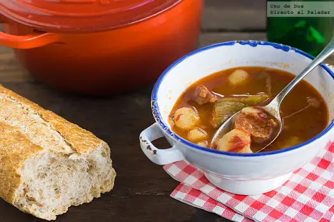 Un reconfortante plato de patatas a la riojana, con chorizo y pimientos, servido en un cuenco blanco con borde azul.