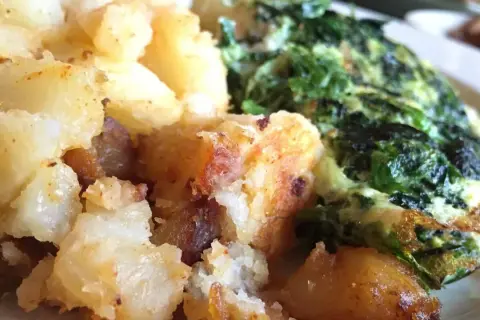 Patatas doradas y crujientes junto a unas espinacas con patatas, un plato casero y reconfortante.