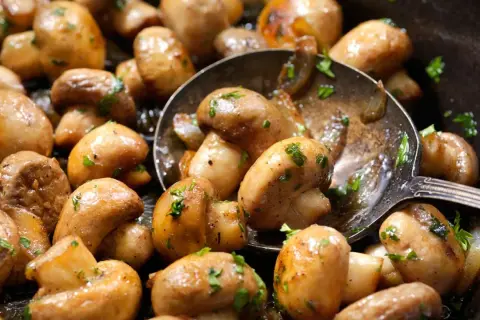 Champiñones dorados y jugosos, recién salidos de la freidora de aire, con perejil fresco picado. ¡Una delicia fácil y rápida!