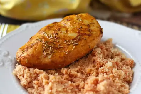 Pechuga de pollo dorada y jugosa, cocinada en freidora de aire, servida sobre una cama de cuscús.