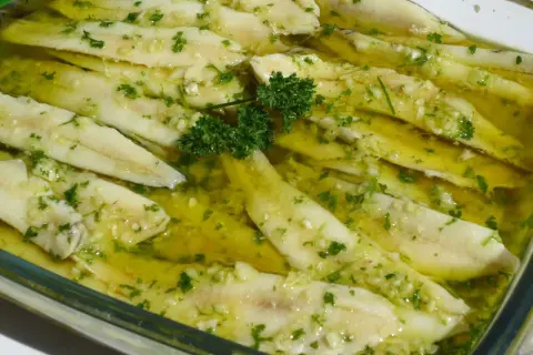 Boquerones en vinagre, frescos y listos para disfrutar, con ajo picado y perejil en aceite de oliva.