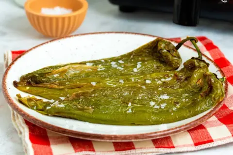 Pimientos verdes asados en freidora de aire, servidos en plato blanco con sal gruesa.