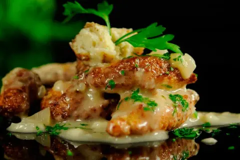 Deliciosas albóndigas de rape doradas, cubiertas con una cremosa salsa y perejil fresco.