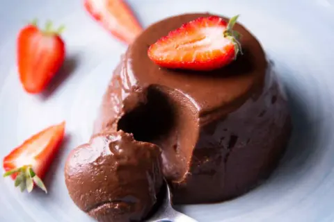 Delicioso flan de chocolate cremoso, decorado con fresas frescas. ¡Un postre irresistible!