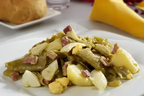 Deliciosa ensalada de judías verdes con trocitos de jamón y huevo duro, acompañada de patatas. Un plato casero y sabroso.