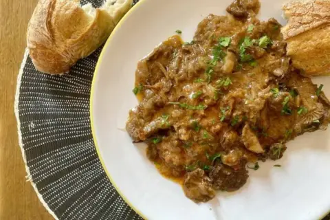 Delicioso fricando de ternera con trozos de pan crujiente, listo para disfrutar.